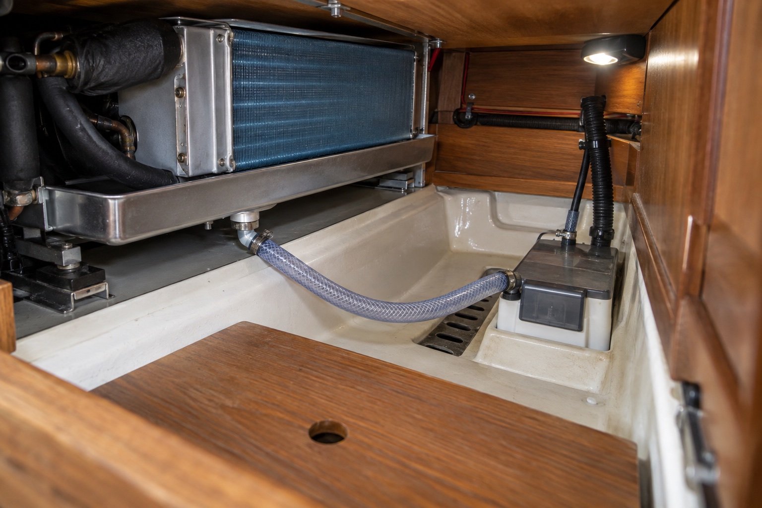Accessible yacht air-conditioning evaporator tray with a continuously falling condensate hose leading to a sump